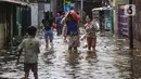Warga melintasi banjir di salah satu permukiman penduduk di Kawasan Cengkareng Barat, Jakarta Barat, Kamis (30/1/2025). (Liputan6.com/Angga Yuniar)