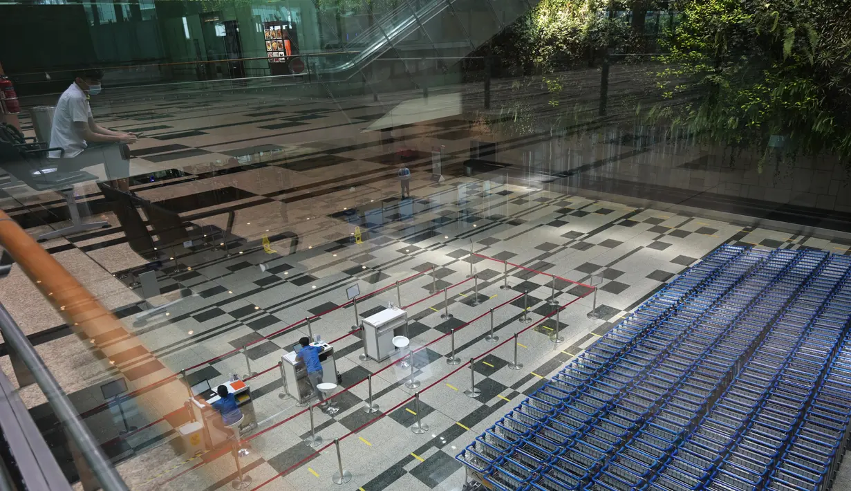 Dua petugas bekerja di aula kedatangan di terminal 3 Bandara Changi Singapura (7/12/2020). Bandara Changi Singapura tampak sepi jelang menyambut Natal di Tengah Pandemi COVID-19. (Xinhua/Then Chih Wey)