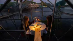 Pengunjung duduk bersulang dalam kabin kaca berkonsep "quarantine greenhouses" selama uji coba, ketika Belanda berjuang melawan penyebaran COVID-19, di restoran Mediamatic, Amsterdam pada 5 Mei 2020. (AP/Peter Dejong)