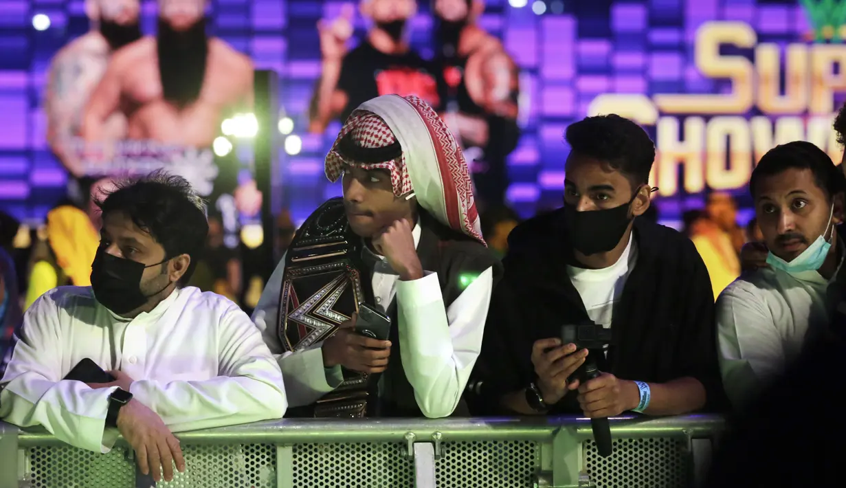 Penggemar gulat mengenakan masker ketika mereka menonton pertandingan gulat WWE Super ShowDown di Riyadh, Arab Saudi, Kamis (27/2/2020). Pemerintah Arab Saudi pada hari Kamis, 27 Februari 2020 resmi menghentikan sementara izin umrah bagi seluruh negara. (AP Photo/Amr Nabil)