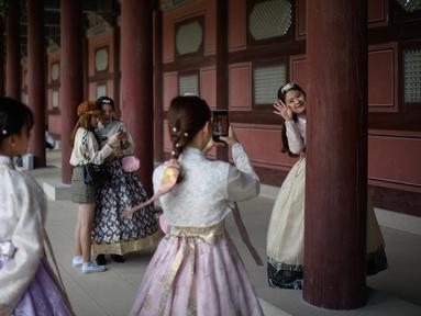 Pengunjung mengenakan pakaian tradisional Korea, Hanbok sambil berpose di istana Gyeongbokgung, Seoul, Rabu (26/9). Korea Selatan sedang menikmati hari terakhir dari liburan Chuseok atau Hari Thanksgiving. (AFP PHOTO / Ed JONES)