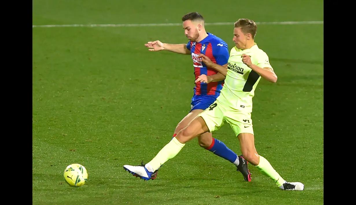 Pemain Eibar, Edu Exposito (kiri) berusaha menghadang pemain Atletico Madrid, Marcos Llorente pada laga pekan ke-19 La Liga di Estadio Municipal de Ipurua, Jumat (23/1/2021). Atletico Madrid meraih kemenangan 2-1 atas Eibar. (Foto: AFP/Ander Gillenea)