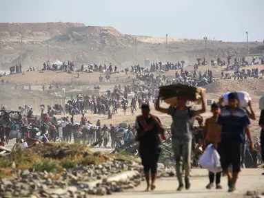 Orang-orang berjalan membawa tas-tas berisi bantuan kemanusiaan yang mereka terima di pusat distribusi yang dikelola oleh Yayasan Kemanusiaan Gaza (GHF) yang didukung Ameriks Serikat dan Israel, di koridor Netzarim, Nuseirat, Jalur Gaza tengah, pada 26 September 2025. (Eyad BABA/AFP)