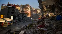 Seorang pria membawa ember saat berjalan di antara bangunan yang hancur setelah gempa di Samandag, Turki, 16 Februari 2023. Otoritas Turki mengatakan setidaknya 38.044 orang telah tewas, sementara pemerintah Suriah dan PBB mengatakan lebih dari 5.800 orang tewas di sana. (AP Photo/Francisco Seco)