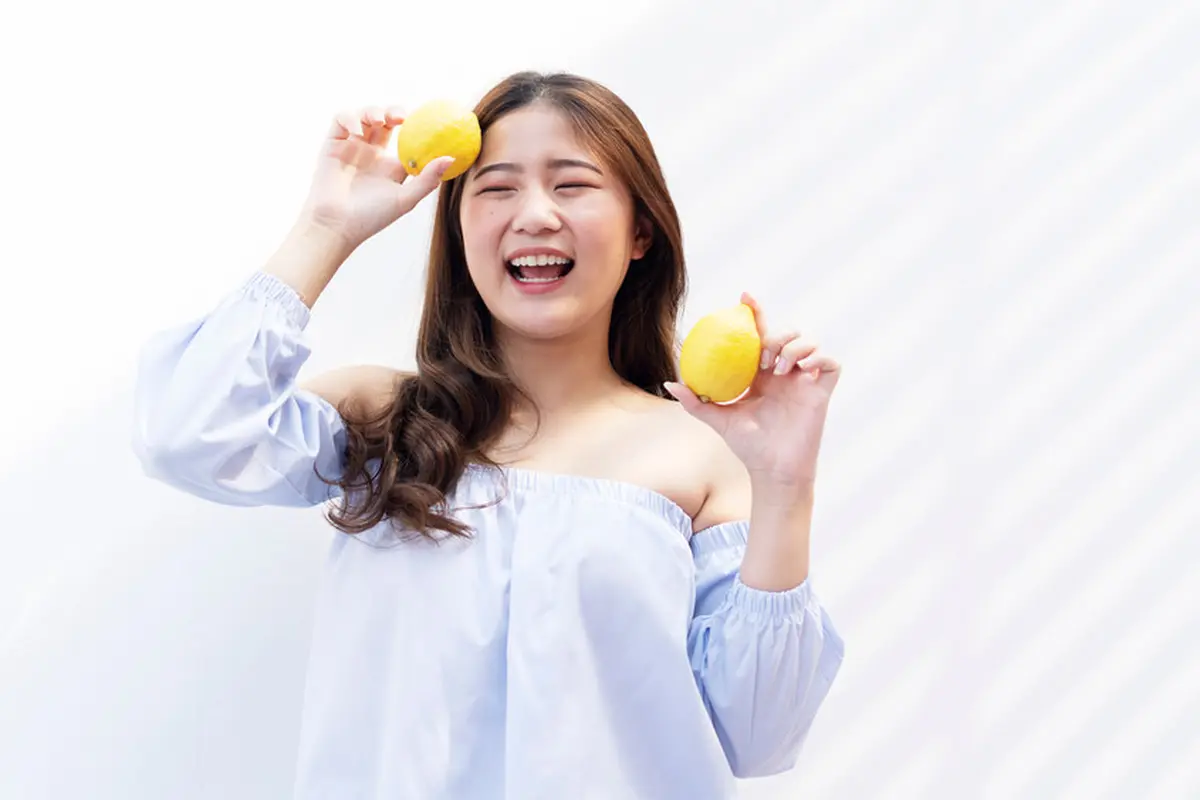 perempuan tersenyum membawa jeruk
