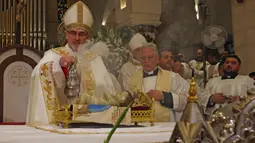 Patriark Latin Yerusalem, Pierbattista Pizzaballa memimpin Misa Malam Natal di Kompleks Gereja Kelahiran Yesus, Bethlehem, Tepi Barat, Minggu (25/12/2022). Setelah dua tahun tutup karena COVID-19, jemaat kembali menghadiri ibadah tersebut kendati jumlahnya tidak sebanyak sebelum pandemi. (Ahmad Gharabli/Pool Photo via AP)