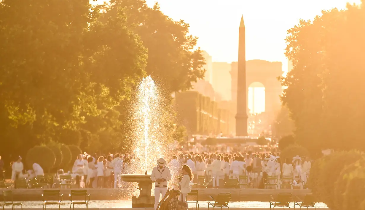 Peserta dalam balutan serba putih  berkumpul untuk Dinner en Blanc atau "makan malam putih" di Tuileries Gardens, Paris, Kamis (6/6/2019). Acara selesai ketika tengah malam dan peserta diminta untuk meninggalkan tempat acara dengan tertib dan tidak meninggalkan barang bawaannya (Lucas BARIOULET/AFP)