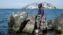 Gambar 5 Oktober 2018, seorang wanita membersihkan perabotannya di pulau Usingo di seberang pulau Migingo, Danau Victoria. Pada jarak hanya beberapa meter dari Migingo, terdapat Pulau besar dan tak penghuni bernama Usingo. (Yasuyoshi CHIBA/AFP)
