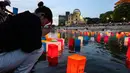 Foto yang diambil pada tanggal 6 Agustus 2024 ini menunjukkan seorang wanita yang sedang berdoa saat lentera dilepaskan ke Sungai Motoyasu, di seberang Kubah Bom Atom dekat Taman Peringatan Perdamaian di Hiroshima. (JIJI Press/AFP/Japan OUT)