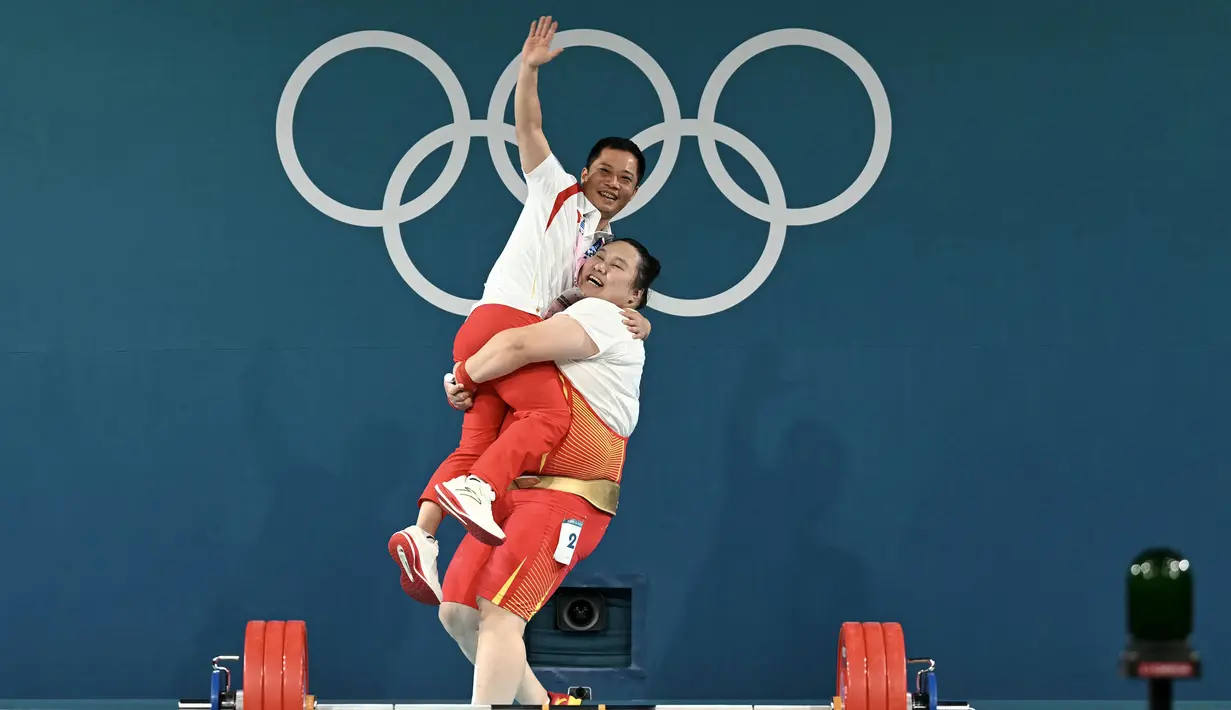 Lifter China, Li Wenwen mengagkat pelatihnya saat melakukan selebrasi setelah meraih medali emas cabang olahraga angkat besi +81kg putri Olimpiade Paris 2024 di South Paris Arena, Paris, Prancis, Sabtu (11/08/2024).  (AFP/Arun Sankar)