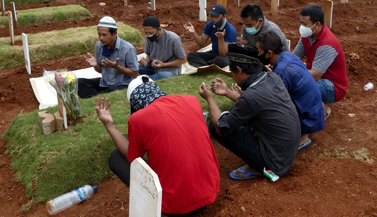 Keluarga korban yang meninggal karena virus corona COVID-19 berdoa saat pemakaman di Jakarta, Rabu (15/4/2020). Hingga sore ini, jumlah kasus COVID-19 di Indonesia sebanyak 5.136 positif, 446 sembuh, dan 469 meninggal dunia. (Bay ISMOYO/AFP)