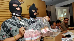 Dua penyidik KPK memperlihatkan uang pecahan Rp100 ribu dalam rilis Operasi Tangkap Tangan (OTT) Ketua DPRD Bangkalan Fuad Amin Imron di Gedung KPK, Jakarta, Selasa (2/12/2014). (Liputan6.com/Miftahul Hayat)