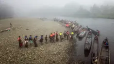 Para imigran mengantre untuk diangkut dari Desa Bajo Chiquito ke Migrants Reception Station di Lajas Blancas, Provinsi Darien, Panama, 23 Agustus 2021. Para imigran dari Haiti dan negara-negara lain tiba di wilayah Panama setelah berjalan kaki selama lima hari di Darien Gap. (Ivan PISARENKO/AFP)
