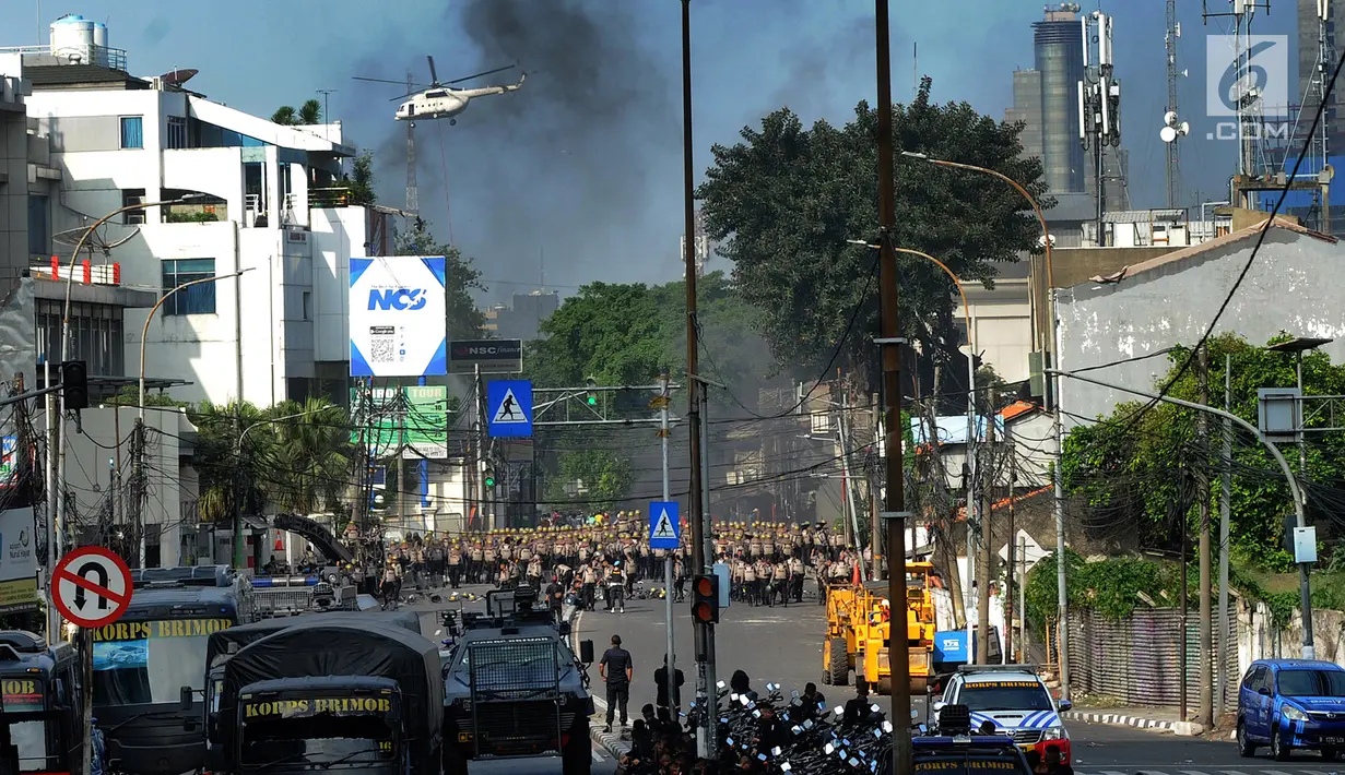 Helikopter water bombing menyiramkan air ke arah ban yang dibakar massa di kawasan Slipi, Jakarta, Rabu (22/5/2019). Air dijatuhkan dari udara ke arah api yang berasal dari ban bekas. (merdeka.com/Arie Basuki)