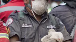 Petugas pemadam kebakaran memegang seekor ayam yang diselamatkan dari zona bencana di Gunung Fuego di Escuintla, Guatemala, (5/6). Puluhan orang tewas akibat bencana tersebut. (AP Photo/Luis Soto)