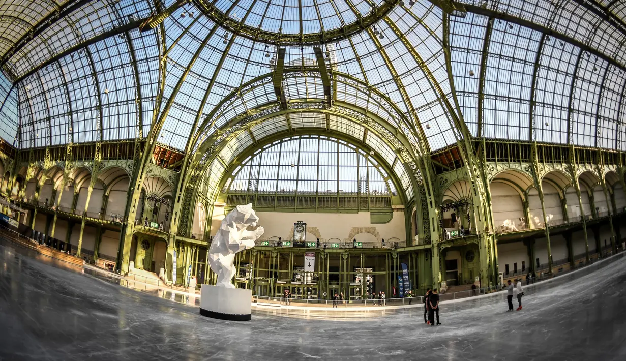 Sebuah  arena ice skating di bawah kubah kaca mewah legendaris, Grand Palais, Paris, Senin (17/12). Tempat seluas 1.800 meter persegi ini menjadi arena ice skating sementara terbesar di Prancis. (STEPHANE DE SAKUTIN / AFP)