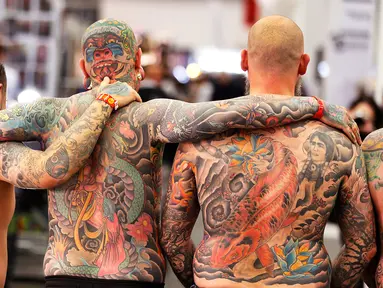 Tiga pria dari Belanda menunjukkan tato di punggung mereka pada hari pertama Konvensi Tattoo Frankfurt di Frankfurt, Jerman (21/4). Ratusan seniman tato ramaikan ajang pertemuan para pecinta seni menggambar tubuh ini. (AP Photo / Michael Probst)