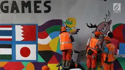 Petugas PPSU Srengseng Sawah menggambar mural bertema Asian Games 2018 di kolong flyover Universitas Indonesia, Depok, Jawa Barat, Jumat (27/7). Perhelatan Asian Games 2018 akan berlangsung di Jakarta dan Palembang. (Liputan6.com/Immanuel Antonius)