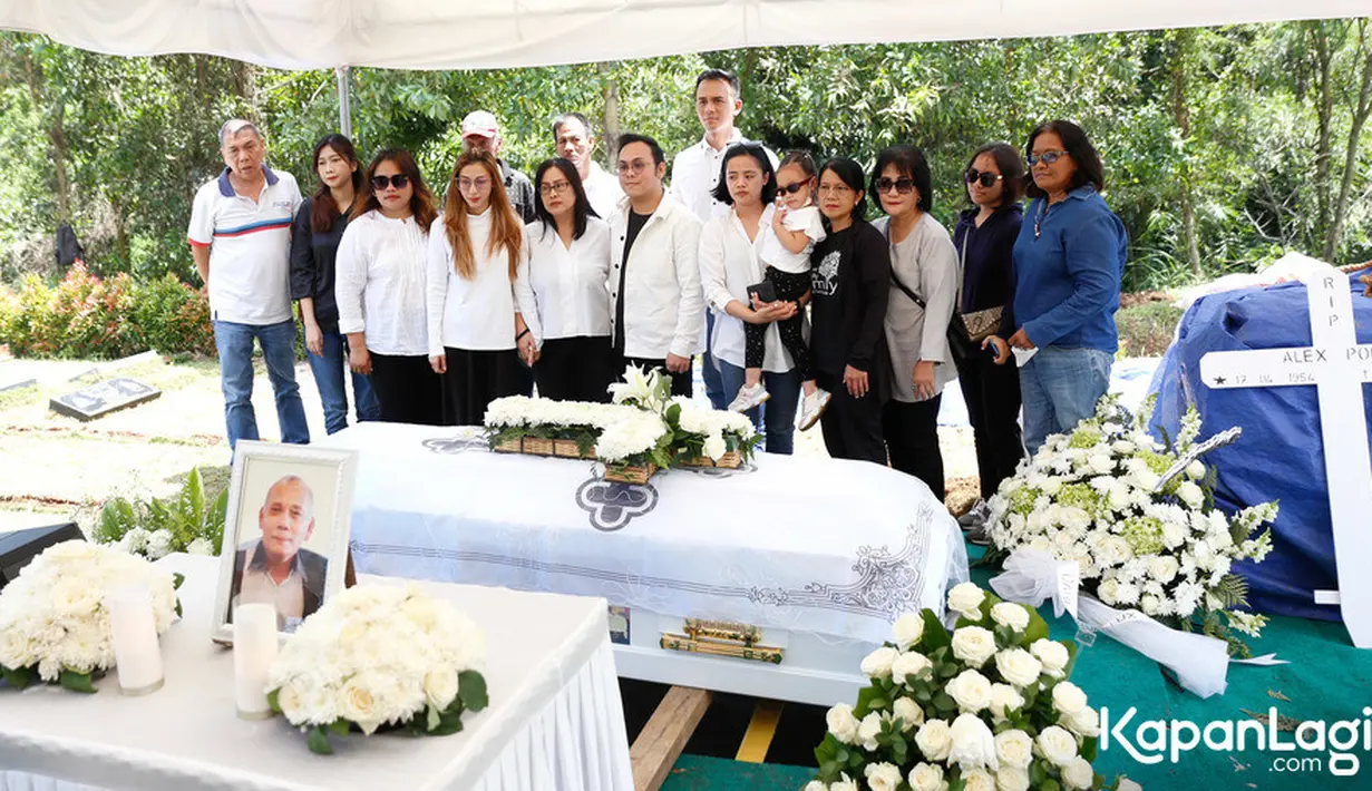 Peti jenazah warna putih yang berisi jenazah Alex Polli siap dimasukkan ke liang lahat. Tampak keluarga menyaksikan prosesi pemakaman ayah Mario Lawalata. [Foto: KapanLagi.com/Bayu Herdianto]