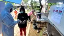 Petugas dengan memakai baju hazmat mengukur suhu warga sebelum mencoblos dalam Pilkada Tangerang Selatan 2020 di TPS 46, Paku Jaya, Serpong Utara, Rabu (9/12/2020). Para petugas KPPS di TPS 46 ini mengunakan seragam APD untuk mengantisipasi penyebaran COVID-19. (merdeka.com/Arie Basuki)