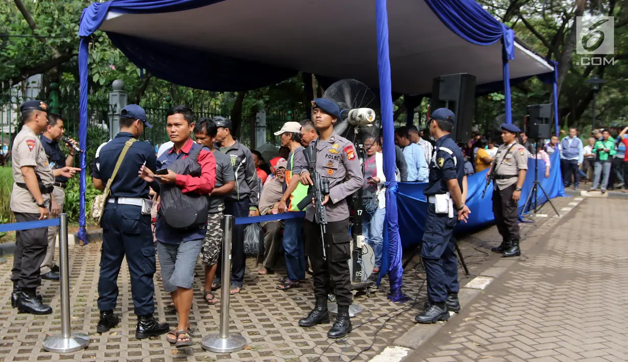 Polisi bersenjata melakukan penjagaan saat warga antre menukar uang pecahan di Lapangan IRTI Monas, Jakarta, Rabu (23/5). Layanan ini menyediakan uang rupiah pecahan kecil bagi masyarakat umum menjelang Lebaran 1439 hijriyah. (Liputan6.com/Arya Manggala)