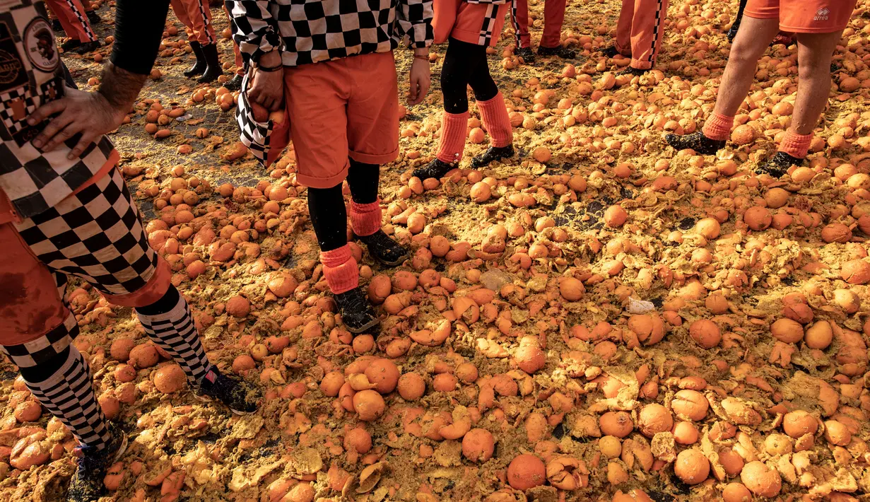 Peserta berdiri di atas tumpukan jeruk yang hancur saat tradisi "perang jeruk" selama Karnaval Ivrea di Turin, Italia, Minggu (3/3). Perang Jeruk ini dikenal juga dengan nama Battaglia Delle Arance atau Carnevale d'Ivrea. (MARCO BERTORELLO/AFP)