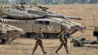 Tentara Israel berjalan melewati tank di dekat perbatasan Gaza-Israel, Jumat (19/10). PM Benjamin Netanyahu berjanji bakal mengambil tindakan tegas apabila warga Palestina masih terus melancarkan serangan ke wilayah Israel. (AP Photo/Ariel Schalit)