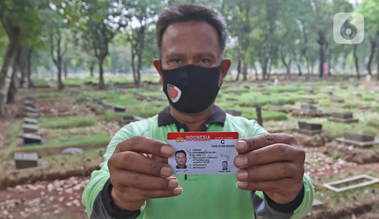 Petugas penggali makam menunjukkan SIM baru di TPU Pondok Ranggon, Jakarta, Kamis (2/7/2020). Dalam rangka HUT ke-74 Bhayangkara, Direktorat Lalu Lintas Polda Metro Jaya memberikan pelayanan penerbitan SIM baru gratis bagi  penggali makam yang menangani korban Covid-19.(Liputan6.com/Herman Zakharia)