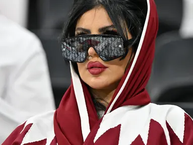 Seorang wanita pendukung Qatar mengenakan kaca mata hitam menghadiri pertandingan Grup A Piala Dunia Qatar 2022 antara Qatar dan Ekuador di Stadion Al-Bayt di Al Khor, utara Doha pada 20 November 2022. (AFP/Glyn Kirk)