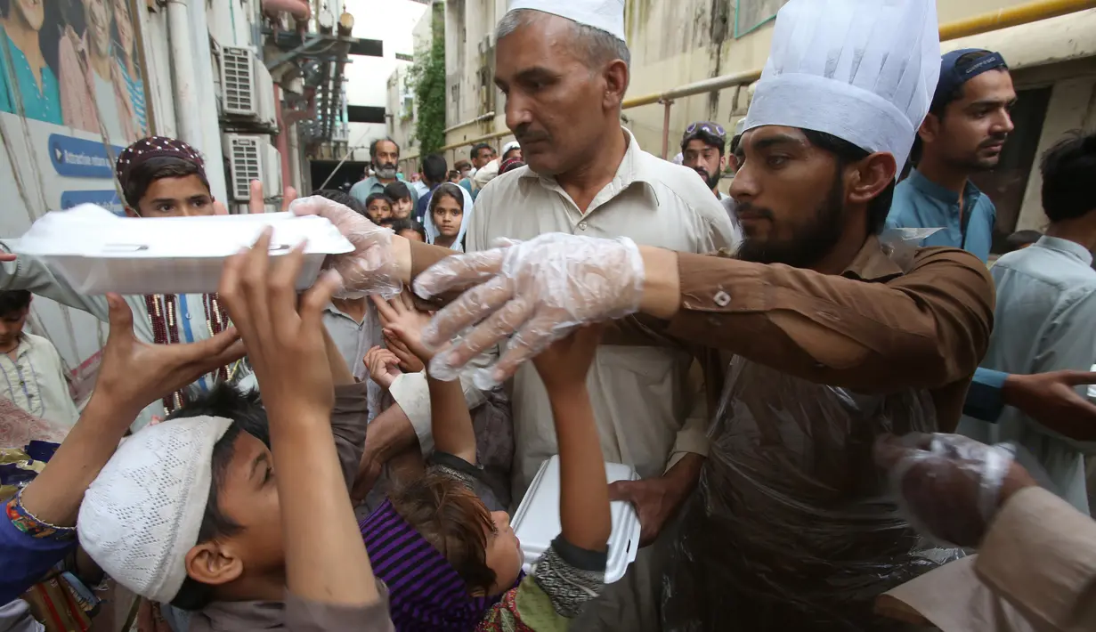 Relawan mendistribusikan kotak makanan untuk orang-orang yang berbuka puasa bersama selama bulan suci Ramadan di Peshawar, Pakistan, Senin (11/5/2020). Warga berbuka puasa bersama setelah pemerintah melonggarkan lockdown terkait pandemi virus corona COVID-19. (AP Photo/ Muhammad Sajjad)