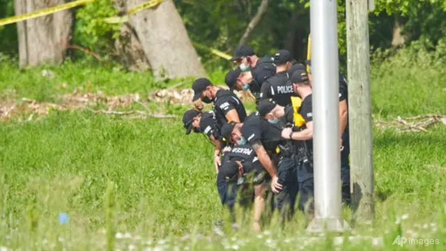 Sederet petugas polisi mencari bukti di lokasi kecelakaan mobil di London, Ontario pada Senin, 7 Juni 2021. Polisi mengatakan banyak orang tewas setelah beberapa pejalan kaki ditabrak mobil pada Minggu malam. (Geoff Robins/The Canadian Press via AP)