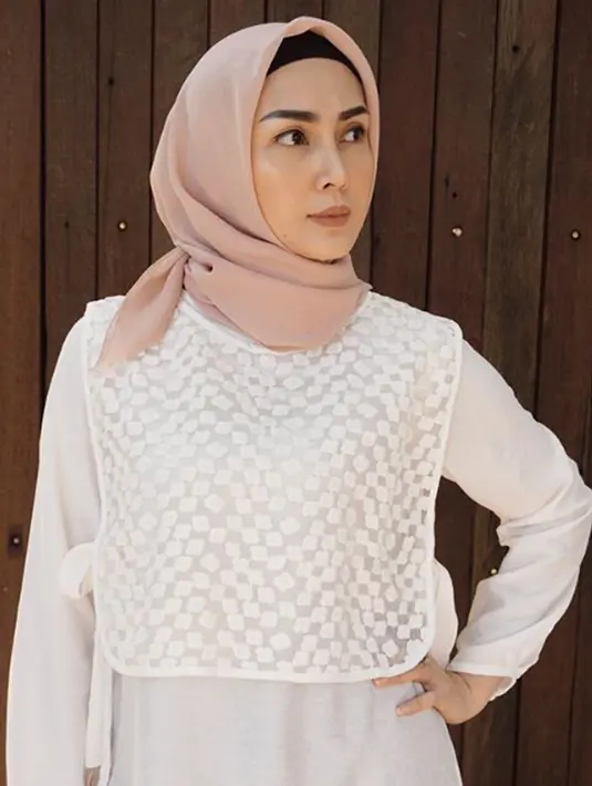 Istri Arie Untung, Fenita Arie saat berpose dengan mengenakan hijab pink dan baju berwarna putih. Langkah Fenita hijrah mengenakan hijab pertama kali diketahui dari unggahan sang suami. (Instagram/ariekuntung)