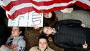 Anna Hurley (15) bersama pengunjuk rasa lainnya berbaring di jalan depan Gedung Putih, Washington, Senin (19/2). Aksi tersebut meminta Presiden Donald Trump menekan Parlemen akan membuat aturan yang memperketat kepemilikan senjata. (AP Photo/Evan Vucci)