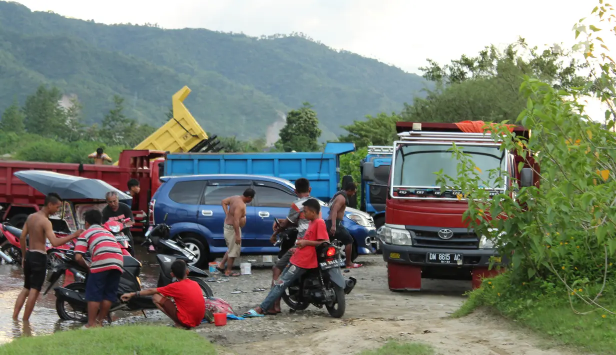 Sejumlah pemilik kendaraan memanfaatkan aliran sungai Bone untuk mencuci di kompleks Jembatan Talumolo II, Kelurahan Talumolo, Gorontalo, Senin (19/11). Tempat itu menjadi kawasan pencucian kendaraan bermotor yang gratis.  (Liputan6.com/Arfandi Ibrahim)