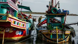 Dua nelayan membawa hasil tangkapannya dari perahu saat tiba di sebuah tempat pelelangan ikan di Brondong, Lamongan, Jawa Timur, Senin (13/3). (AFP Photo/Juni Kriswanto)