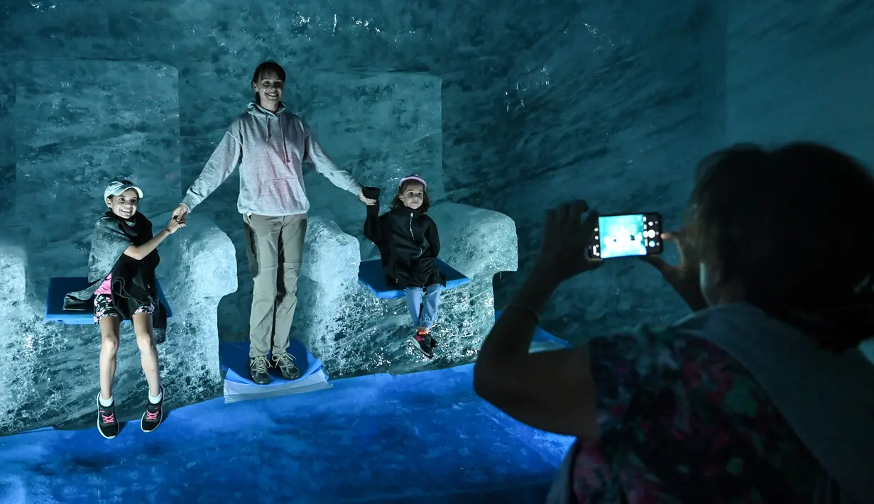 Wisatawan berpose saat mengunjungi gua es yang dikenal dengan "La Grotte de Glace", di gletser Mer de Glace (Lautan Es) di Chamonix-Mont-Blanc, Pegunungan Alpen Prancis, Jumat (19/7/2019). Gua di lereng Mont Blanc ini memiliki panjang 7 km dengan kedalaman 200 meter. (PHILIPPE DESMAZES/AFP)