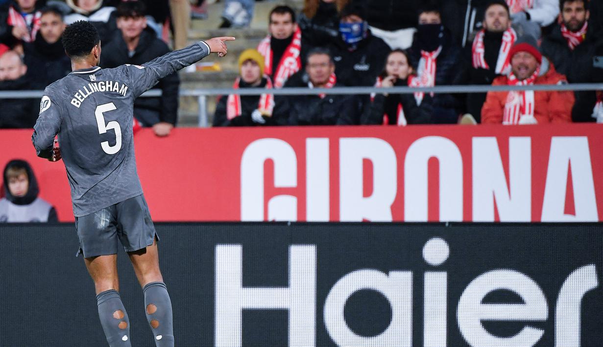 Pemain Real Madrid, Jude Bellingham, melakukan selebrasi di depan suporter Girona pada laga pekan ke-16 Liga Spanyol di Stadion Montilivi pada Sabtu (7/12/2024). (AFP/Josep Lago)