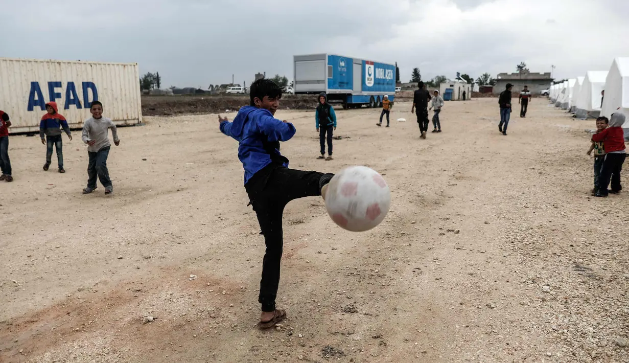 Sejumlah anak pengungsi Suriah bermain sepak bola di sebuah kamp di al-Bil, timur dari kota Azas yang dikuasai pemberontak di Suriah utara (21/4). (AFP Photo/Sameer Al-Doumy)