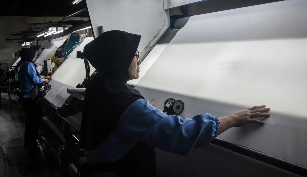 Lonjakan harga bahan baku didorong oleh kenaikan harga minyak mentah dunia, yang memengaruhi biaya bahan baku berbasis petrokimia (seperti polyester) dan biaya logistik. Situasi ini menyebabkan efek domino yang signifikan terhadap industri hilir, termasuk plastik dan kemasan, dengan kenaikan biaya produksi yang mencapai 90–100 persen. Tampak dalam foto, para pekerja memeriksa kain di Trisula Textile Industries, Cimahi, Jawa Barat pada Rabu 22 April 2026, saat para produsen tekstil menghadapi biaya yang lebih tinggi akibat melonjaknya harga bahan baku petrokimia yang terkait dengan kenaikan harga minyak global. (Timur MATAHARI/AFP)