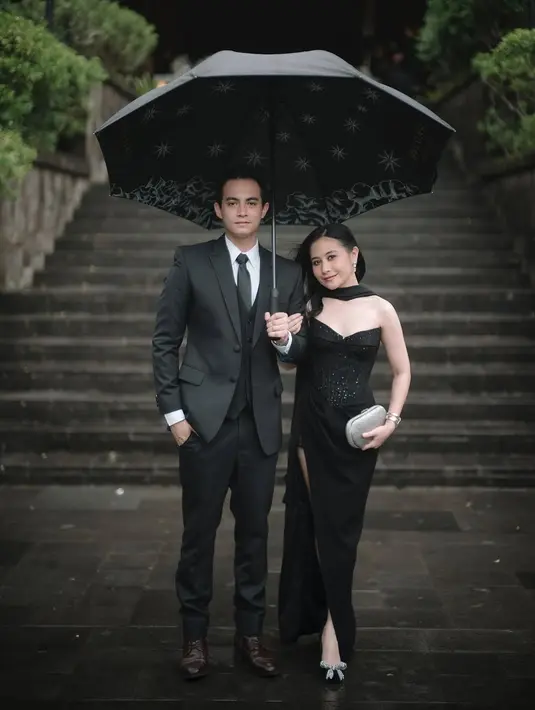 Prilly memilih gaun hitam berpotongan one-shoulder dengan aksen bustier yang memberi kesan klasik sekaligus sensual. Detail embellishment halus pada bagian bodice menambah kesan mewah, sementara belahan tinggi di bagian rok memberikan sentuhan dramatis yang tetap sophisticated. Gaun ini mempertegas siluet tubuhnya dengan cutting yang pas dan elegan.