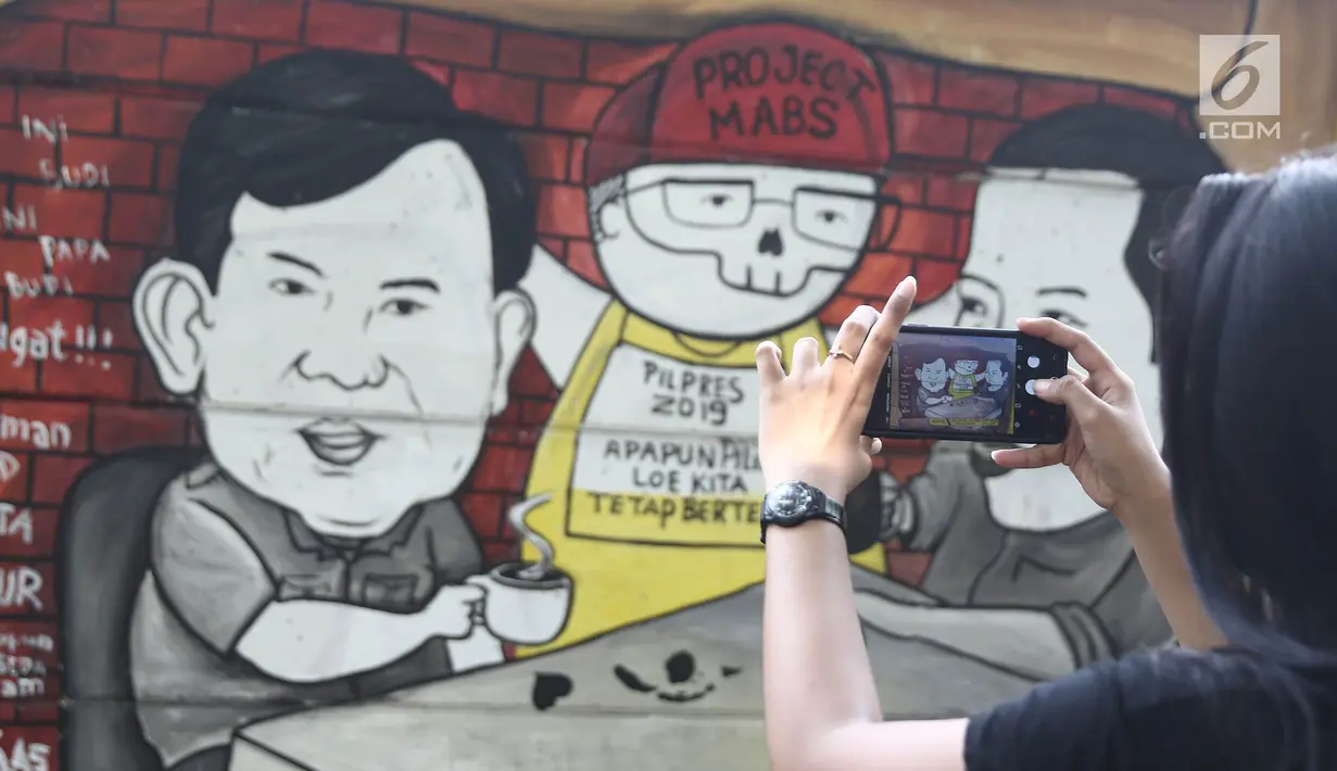 Warga mengabadikan mural Capres Joko Widodo dan Prabowo Subianto di Jalan Juanda, Depok, Jabar, (21/11). Mural tersebut memiliki pesan agar masyarakat tetap damai dan berteman meski berbeda memilih capres di Pilpres 2019. (Liputan6.com/Herman Zakharia)
