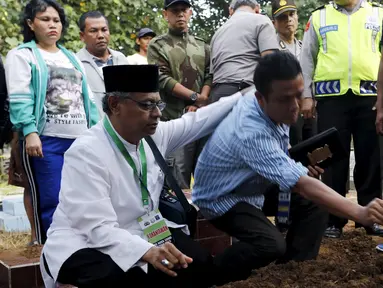 Seorang ulama (kiri) dan Iwan Setiawan, saudara laki-laki terpidana mati Zainal Abidin, saat prosesi pemakaman di TPU di Cilacap, Jateng, Rabu (29/4). Zainal satu-satunya terpidana mati asal Indonesia yang dieksekusi dini hari ini. (REUTERS/Beawiharta)