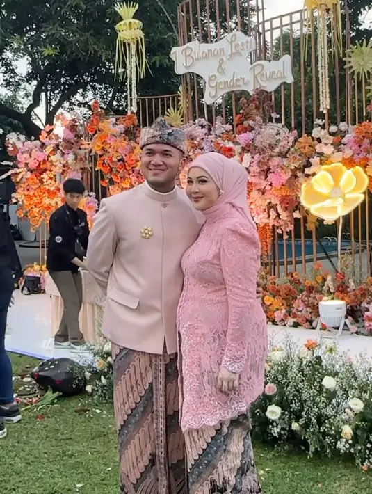 Kesha Ratuliu mengenakan kebaya brokat pink dipadukan kerudung pink polos dengan aksesori anting sebagai ciri khasnya. Sang suami juga mengenakan beskap coklat dipadukan kain batik. [@kesharatuliu05]