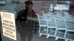 Seorang pria melihat tanda pemberitahuan yang terpasang di depan sebuah toko di Salt Lake City, Utah, Kamis (16/2). 'Sehari Tanpa Imigran' dilakukan untuk menunjukkan amat pentingnya peran para imigran bagi perekonomian di AS. (AP Photo/Jacqueline Larma)