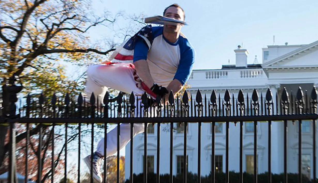 Seorang pria berselimut bendera Amerika Serikat tampak melompati pagar Gedung Putih di Washington, Kamis (26/11). Insiden itu terjadi pada saat Presiden AS Barack Obama sedang berada di dalam Gedung Putih merayakan hari Thanksgiving. (dailymail.co.uk)