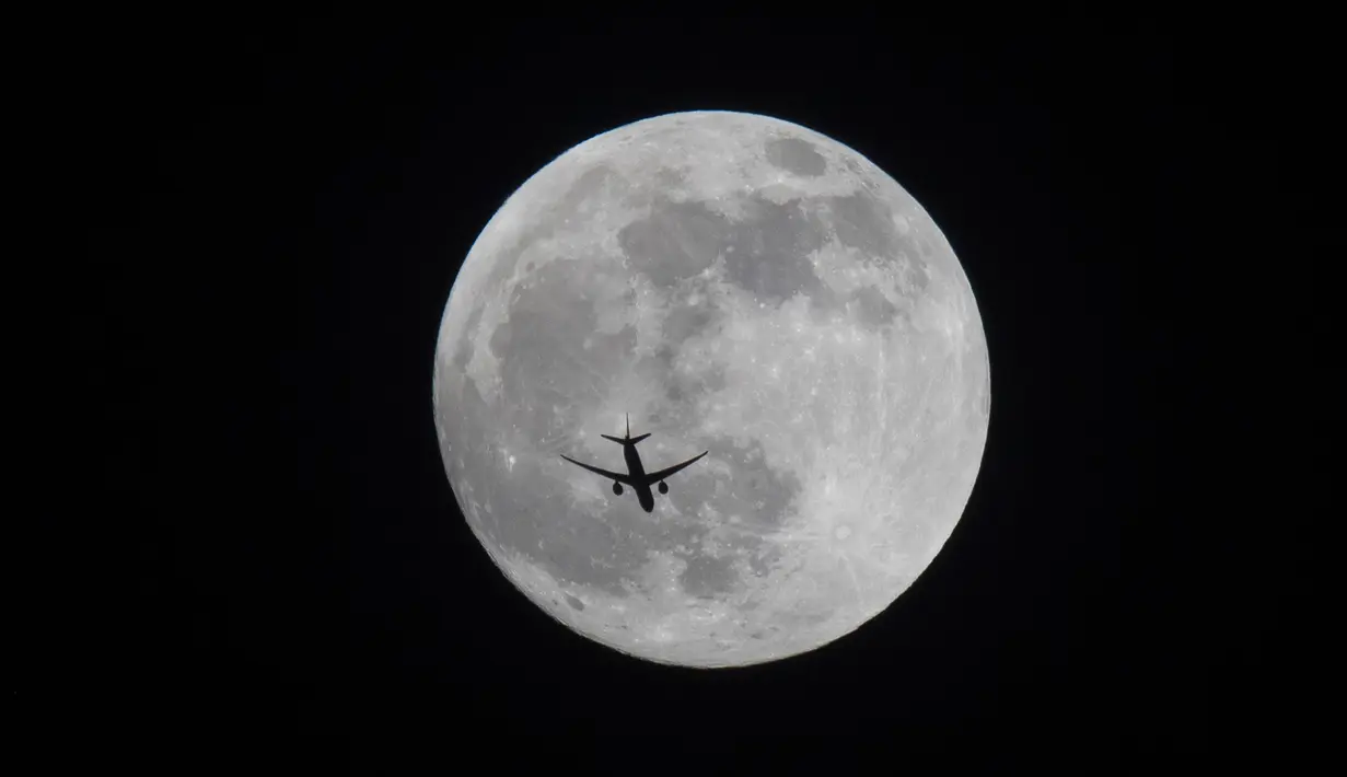 Sebuah pesawat terbang melewati bulan purnama di atas Basra, Irak, Minggu (15/5/2022). (AP Photo/Nabil al-Jurani)