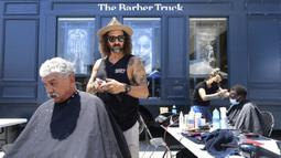 Penata rambut selebriti Jason Schneidman dari The Men's Groomer mencukur rambut Samuel Velasquez saat cukur rambut gratis untuk para tunawisma dalam Los Angeles Mission di Los Angeles, California, Amerika Serikat, 12 Juli 2021. (Frederic J. BROWN/AFP)