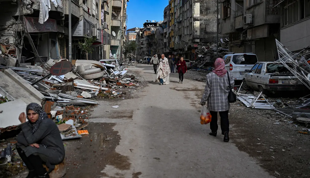 <p>Orang-orang berjalan di sepanjang jalan yang dipenuhi puing-puing saat mereka mencari kerabat di Hatay, sehari setelah gempa berkekuatan 7,8 magnitudo melanda Turki, Selasa (7/2/2023). Hingga 23 juta orang dapat terkena dampak gempa bumi besar yang telah menewaskan ribuan orang di Turki dan Suriah, WHO memperingatkan pada hari Selasa, menjanjikan bantuan jangka panjang. (BULENT KILIC / AFP)</p>