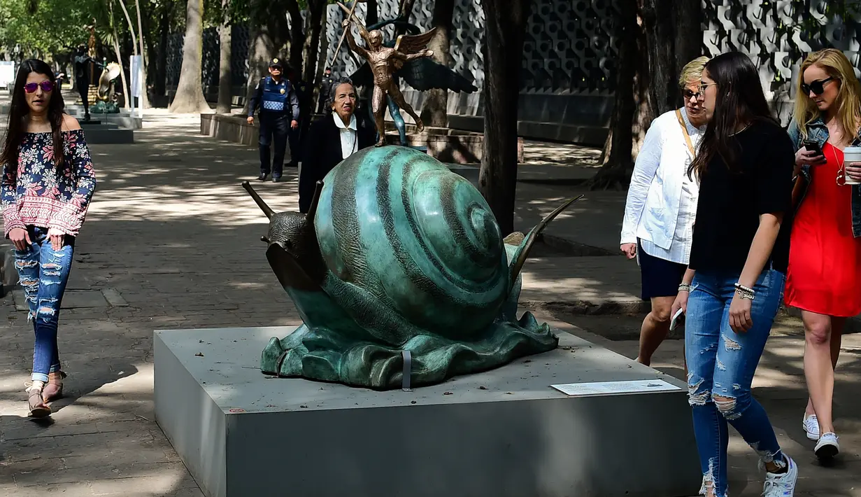 Pengunjung melihat patung "Snail dan Angel" saat pameran "Salvador Dali: Urban Dreams" di Mexico City, Selasa (14/3). Patung-patung tersebut adalah karya seniman asal spanyol yang bernama Salvador Dali. (AFP PHOTO / RONALDO SCHEMIDT)