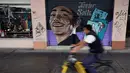 Pengendara sepeda melintas di depan mural penyanyi Javier Solis yang menghiasi pintu toko di Mexico City, Meksiko, 30 Agustus 2017. Mural menjadi salah satu langkah Pemerintah Mexico City melestarikan dan mempercantik ruang publik. (ALFREDO ESTRELLA/AFP)